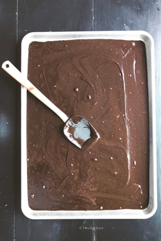 chocolate cake batter spread out in a sheet pan ready to bake