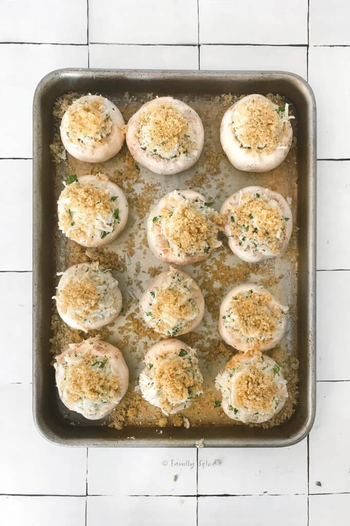 A baking sheet with crab stuffed mushrooms ready to be baked
