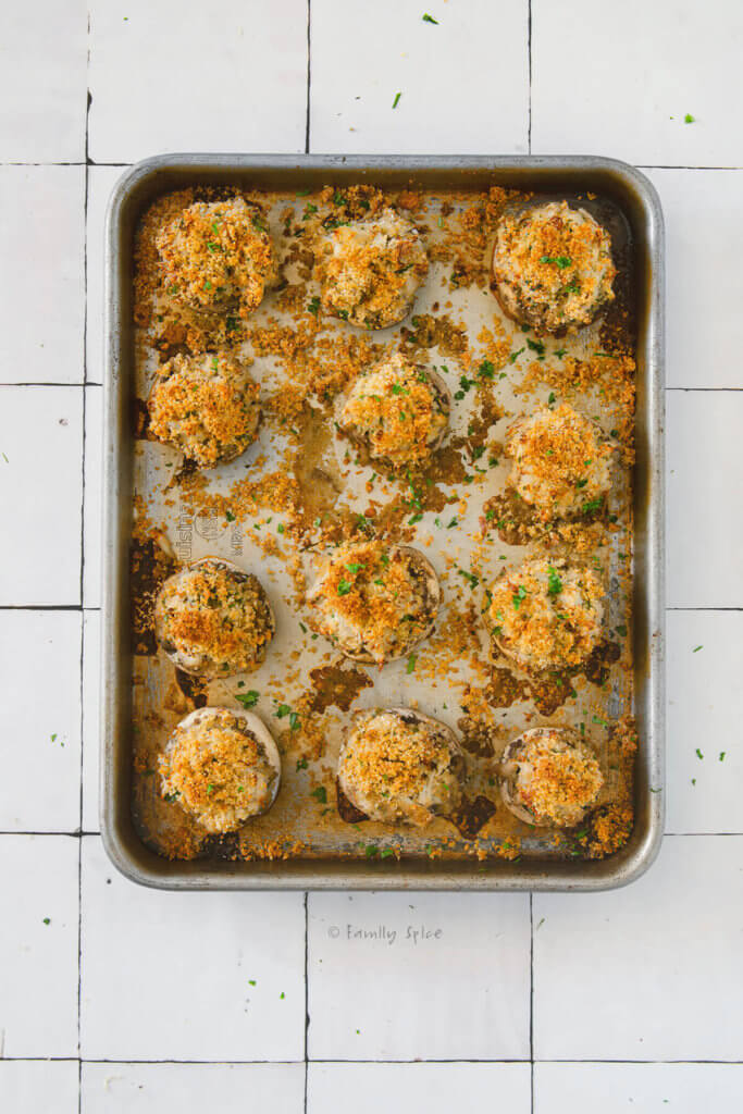 A baking sheet filled with golden brown crab stuffed mushrooms