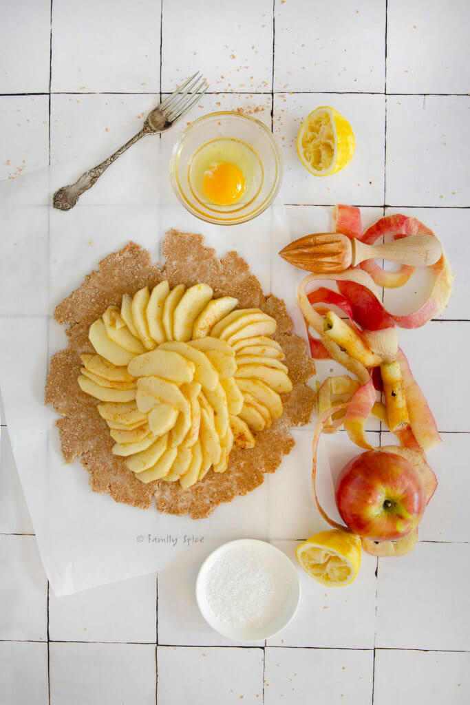 A whole wheat galette crust rolled out with apple slices arranged over it