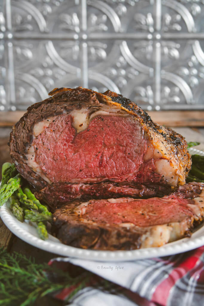 A prime rib roast cooked to medium rare and cut open on a white serving platter