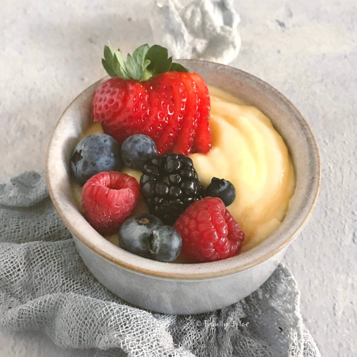 Closeup of a small grey bowl with pastry cream and fresh berries on top