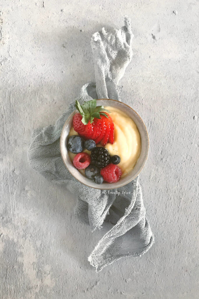 Overhead shot of a small grey bowl with pastry cream and fresh berries on top
