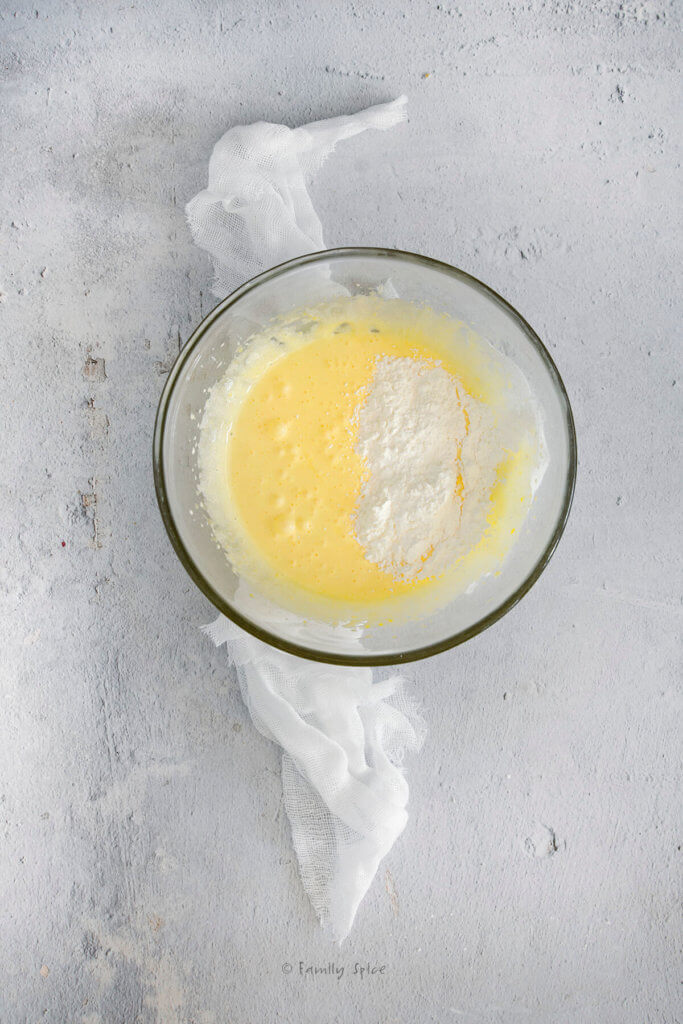 A glass mixing bowl with cornstarch sprinkled over whipped egg mixture