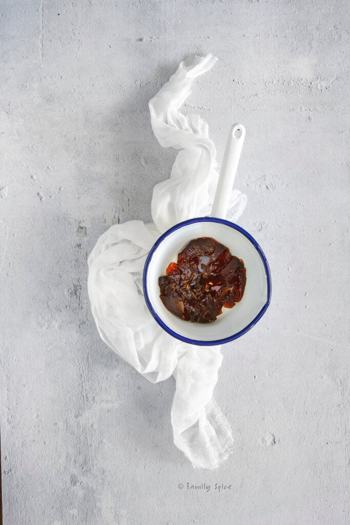 Melting pomegranate jelly in a white enamel sauce pan
