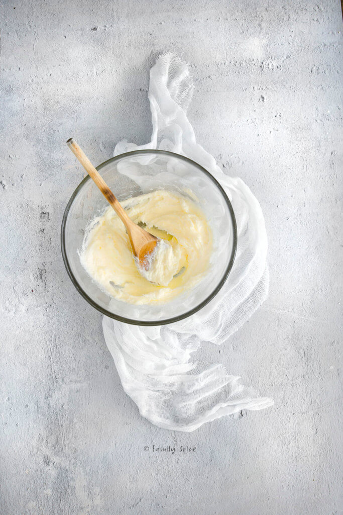 Butter creamed with sugar using a wooden spoon in a glass mixing bowl
