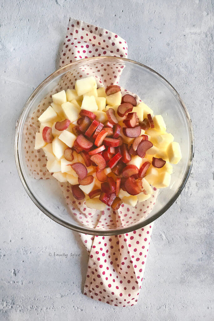 A glass bowl with chopped apples and rhubarb mixed together