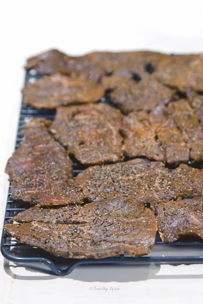 Marinated slices of meat on a rack ready to be oven dried for beef jerky