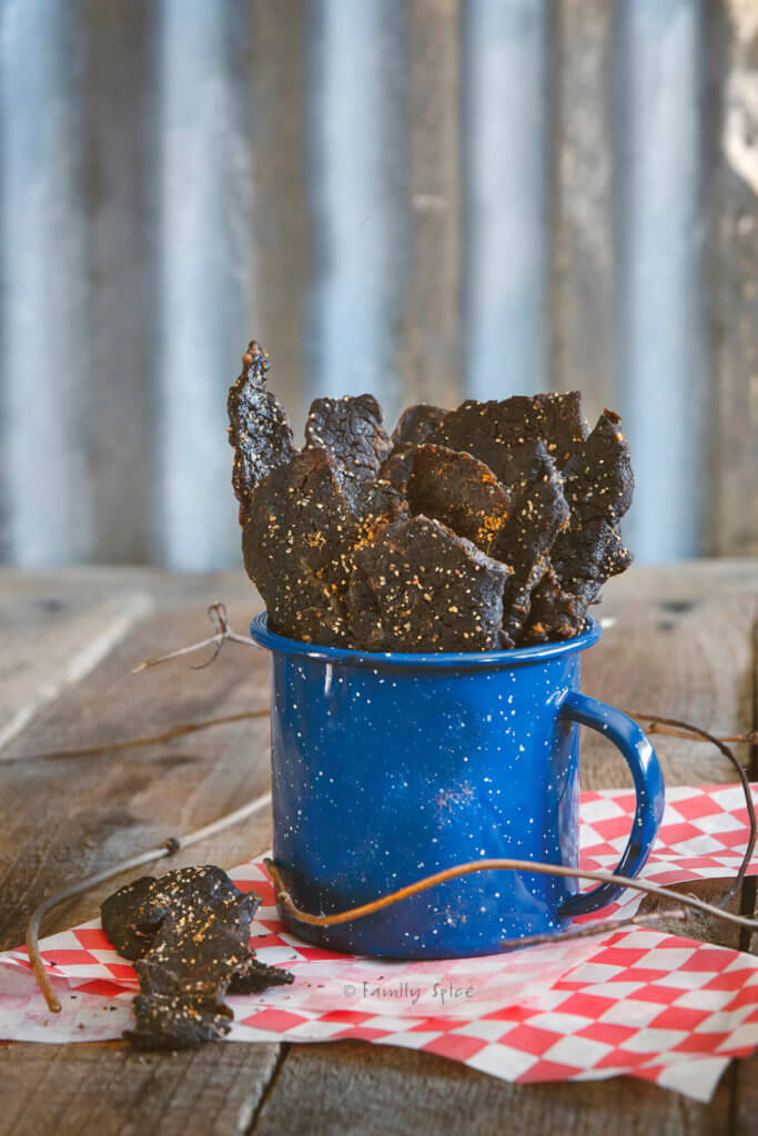 A blue cup filled with the best homemade oven beef jerky