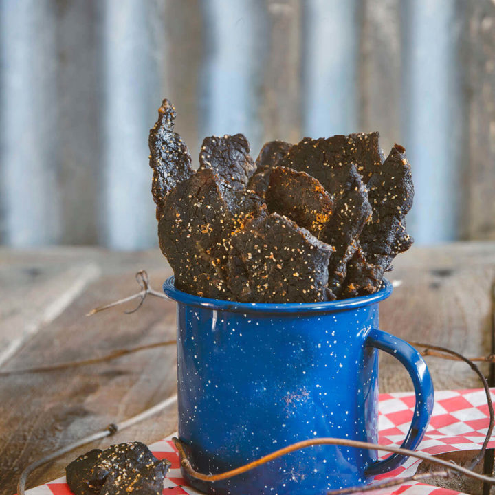 A blue cup filled with the best homemade oven beef jerky