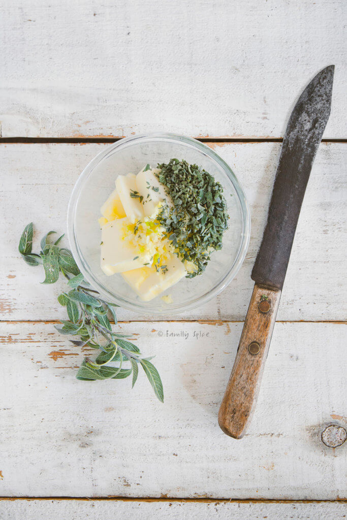 A small bowl with butter, lemon zest and chopped herbs in it