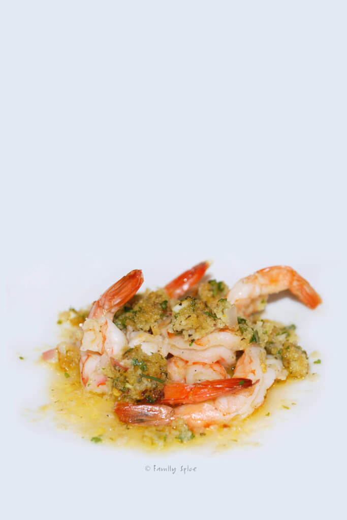 Closeup of a white dish with a few pieces of baked shrimp scampi on it