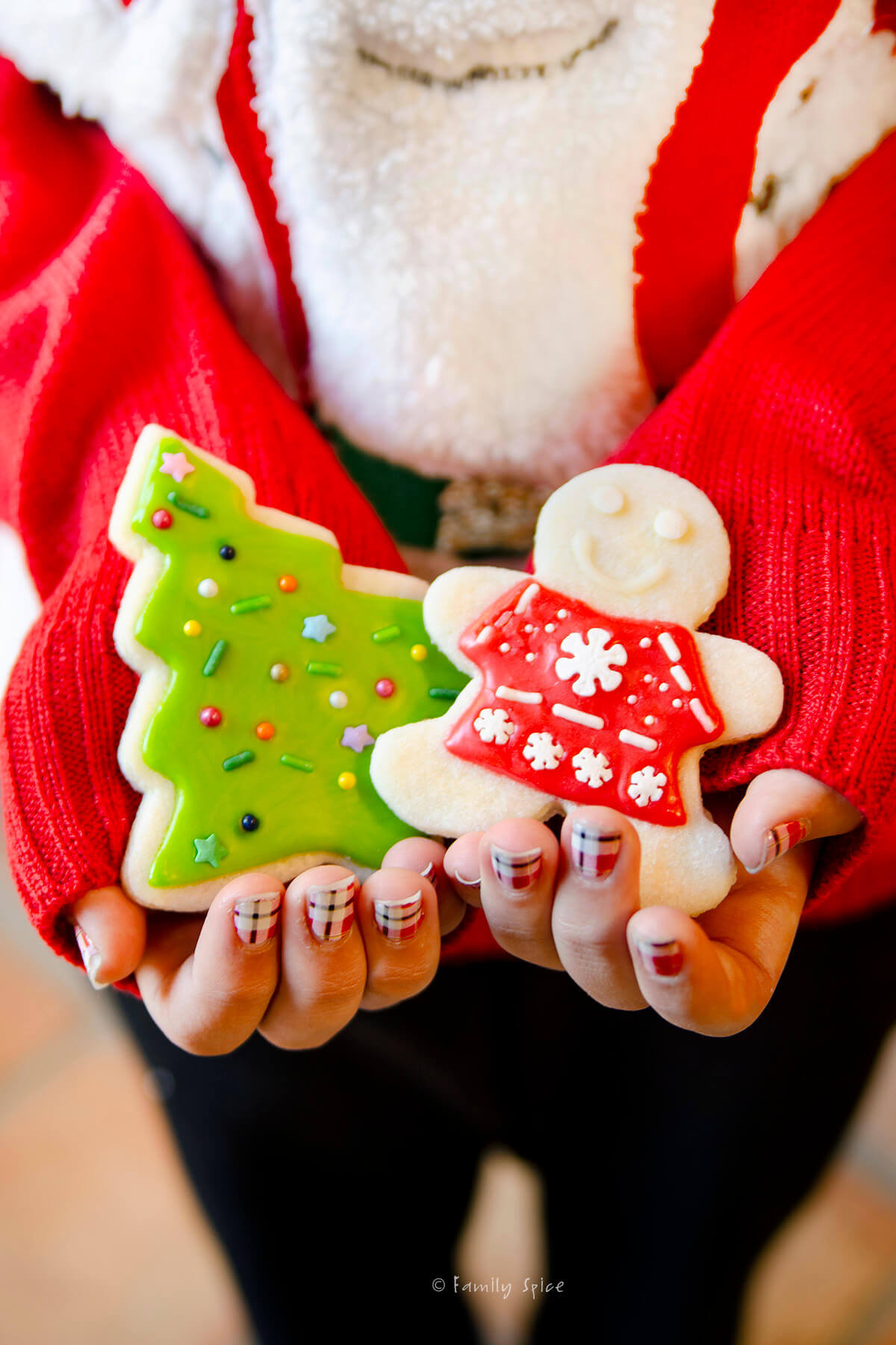 A girl's hand with two decorated christmas sugar cookies