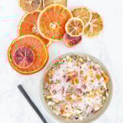 Overhead shot of a bowl and spoon filled with orange lemon salt blend with assorted dried citrus slices