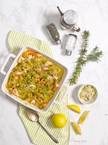 Baked shrimp scampi in a square baking dish with ingredients around it