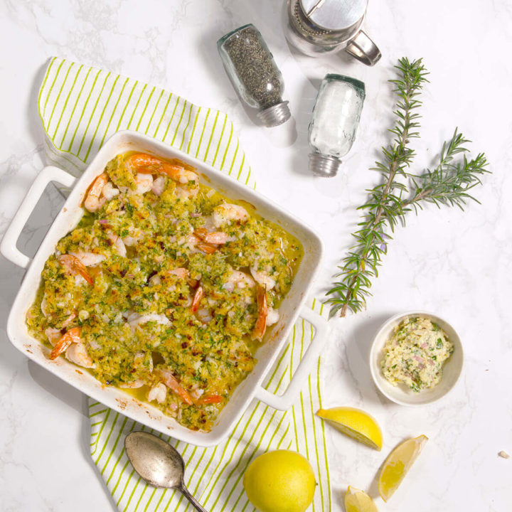 Baked shrimp scampi in a square baking dish with ingredients around it