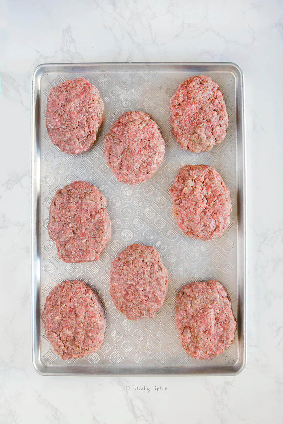 Meat patties formed on a baking sheet to make salisbury steak