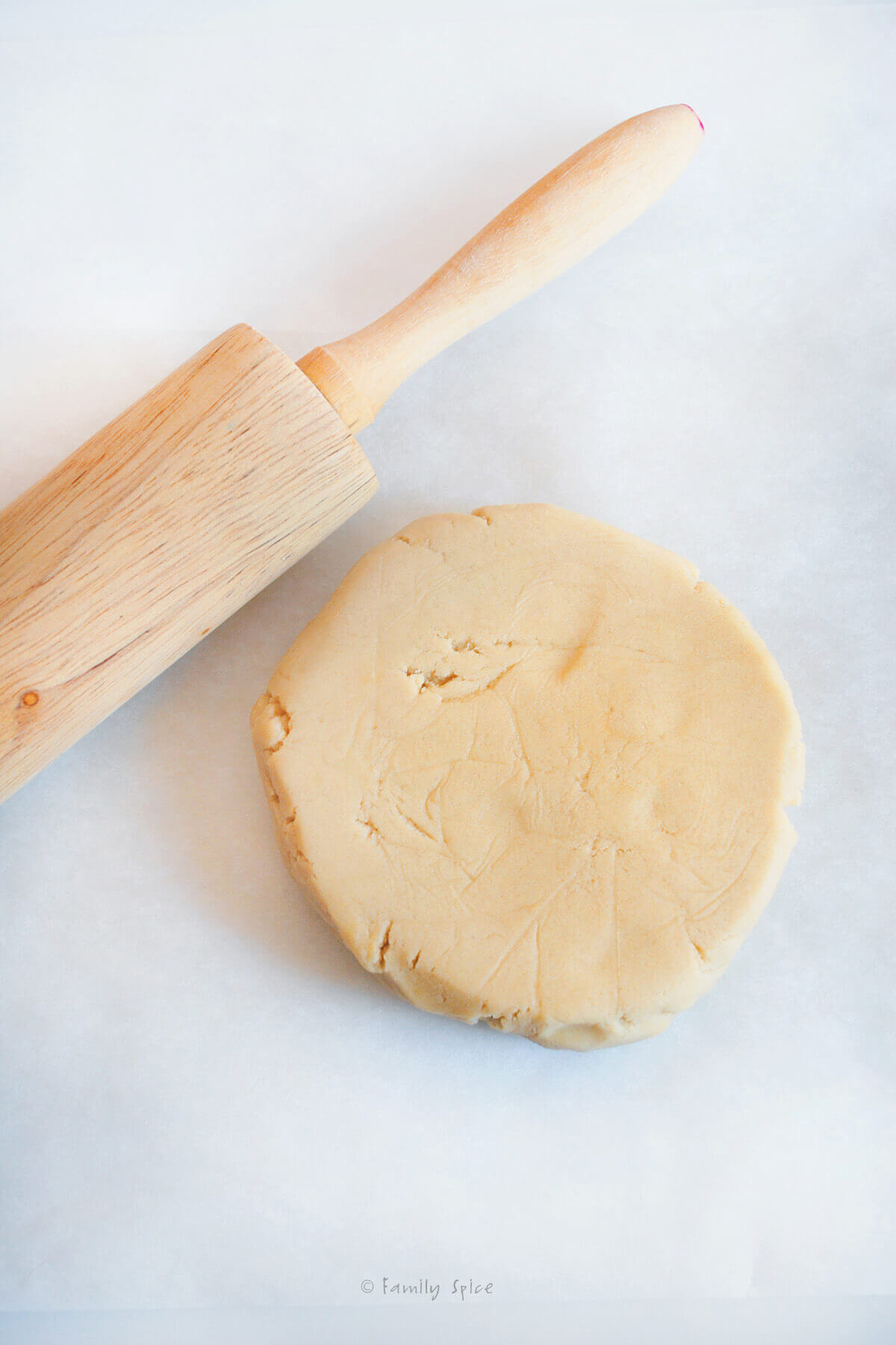 A rolling pin with sugar cookie dough next to it