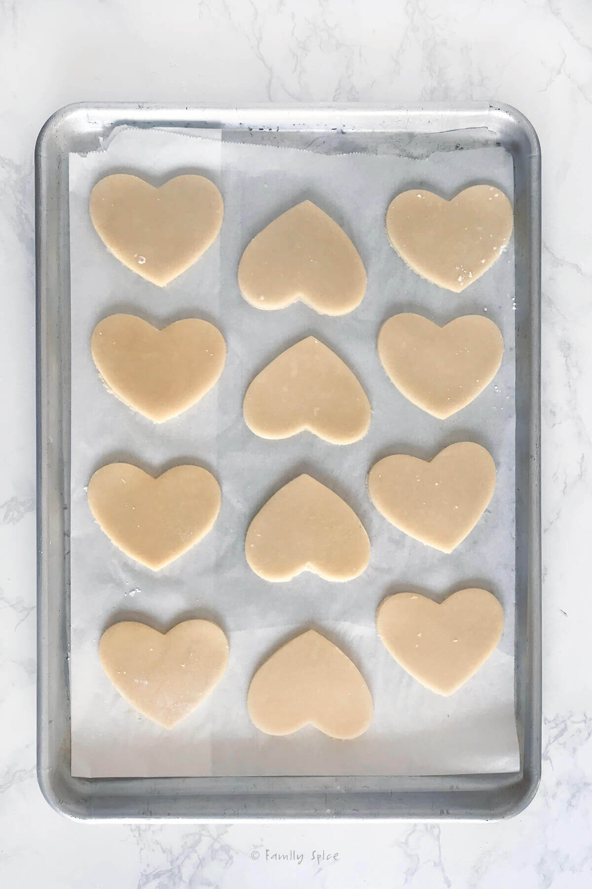 A baking sheet with raw heart sugar cookies on it
