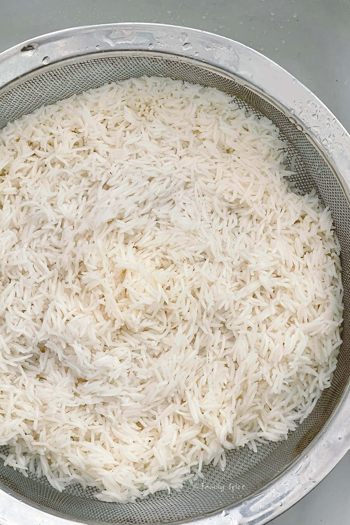 White basmati rice parboiled and drained in a mesh strainer