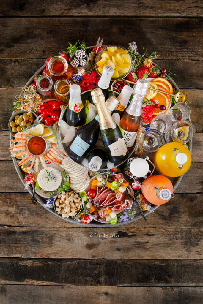 Top view of a fully loaded champagne board in a large round metal tray