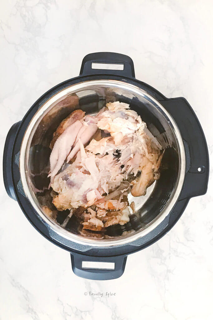 An instant pot with a chicken carcass and chicken feet in it