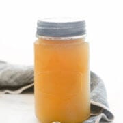 A mason jar filled with chicken bone broth with a napkin next to it
