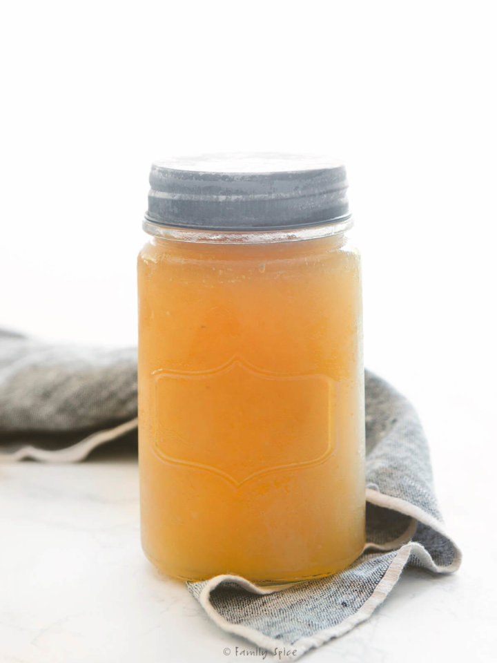 A mason jar filled with chicken bone broth with a napkin next to it