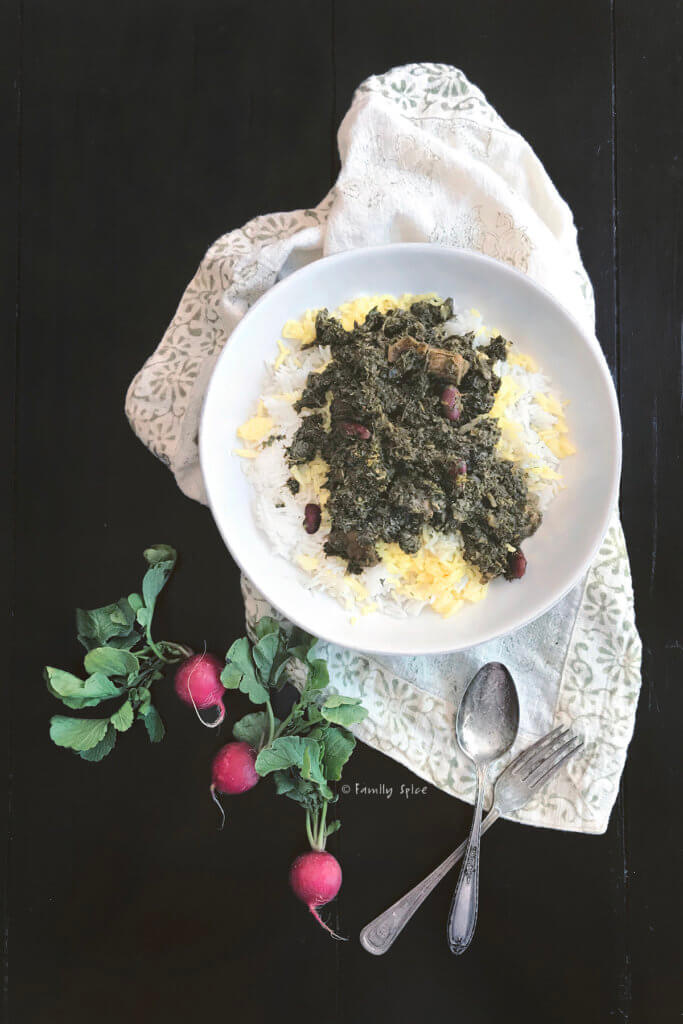 Top view of a plate with rice and Instant Pot Gormeh Sabzi (Persian Herb Stew with Beef) with radishes next to it