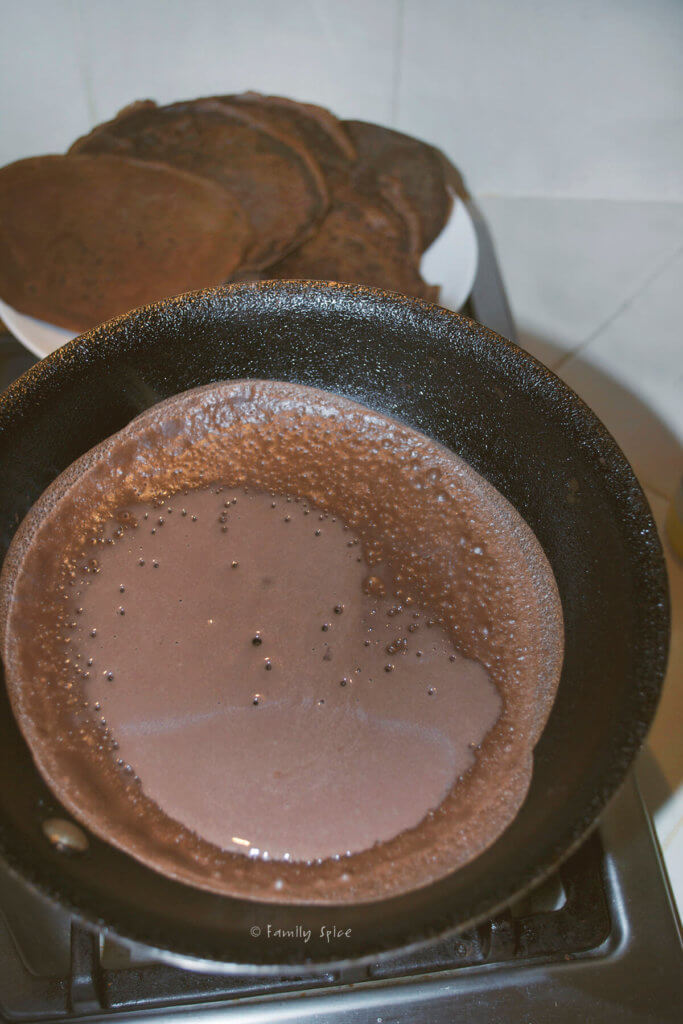 Chocolate crepe slowly cooking in a nonstick pan
