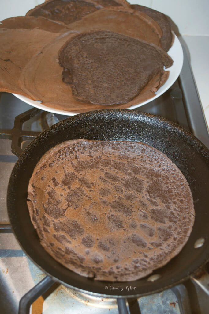 Chocolate crepe flipped over and finishing cooking in a nonstick pan