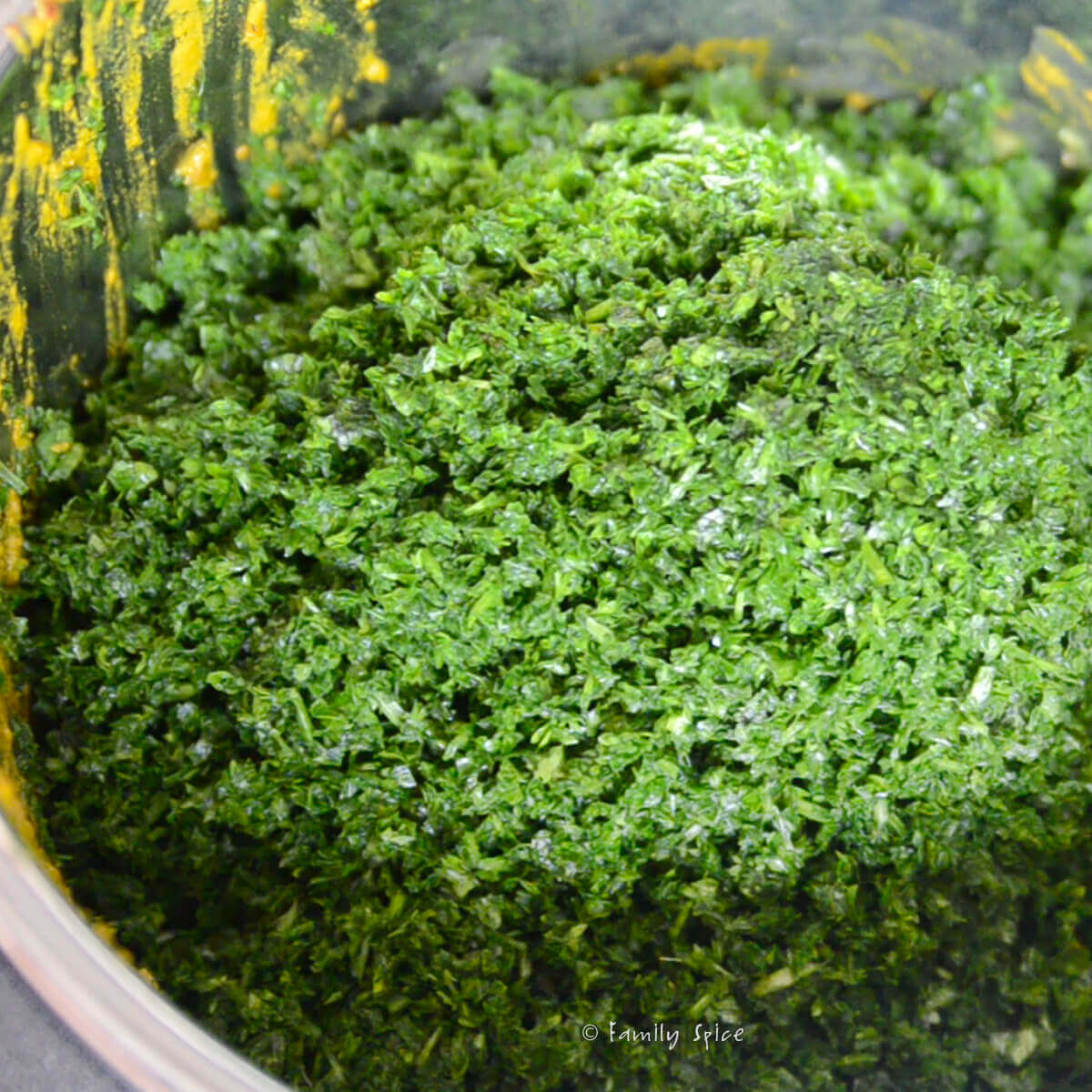 Adding chopped herbs into the instant pot to make gormeh sabzi