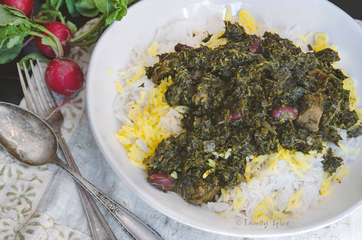 Closeup of a plate with basmati rice topped with saffron and gormeh sabzi with radishes next to it