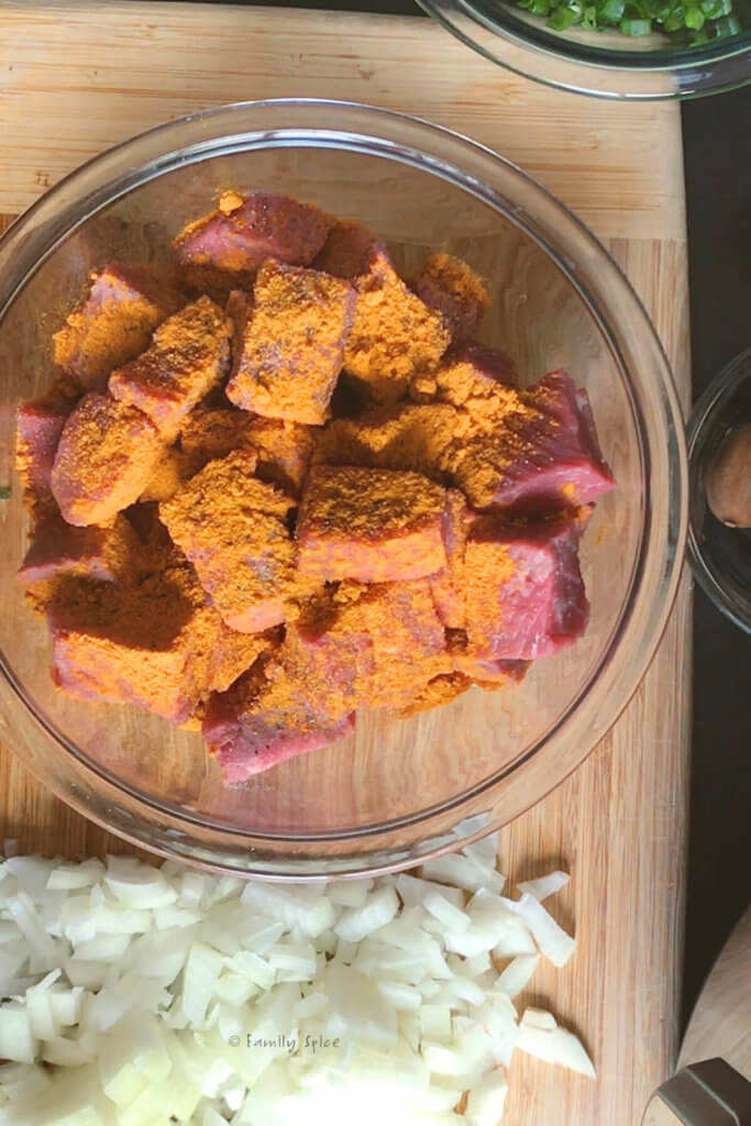Beef stew meat in a mixing bowl seasoned with turmeric