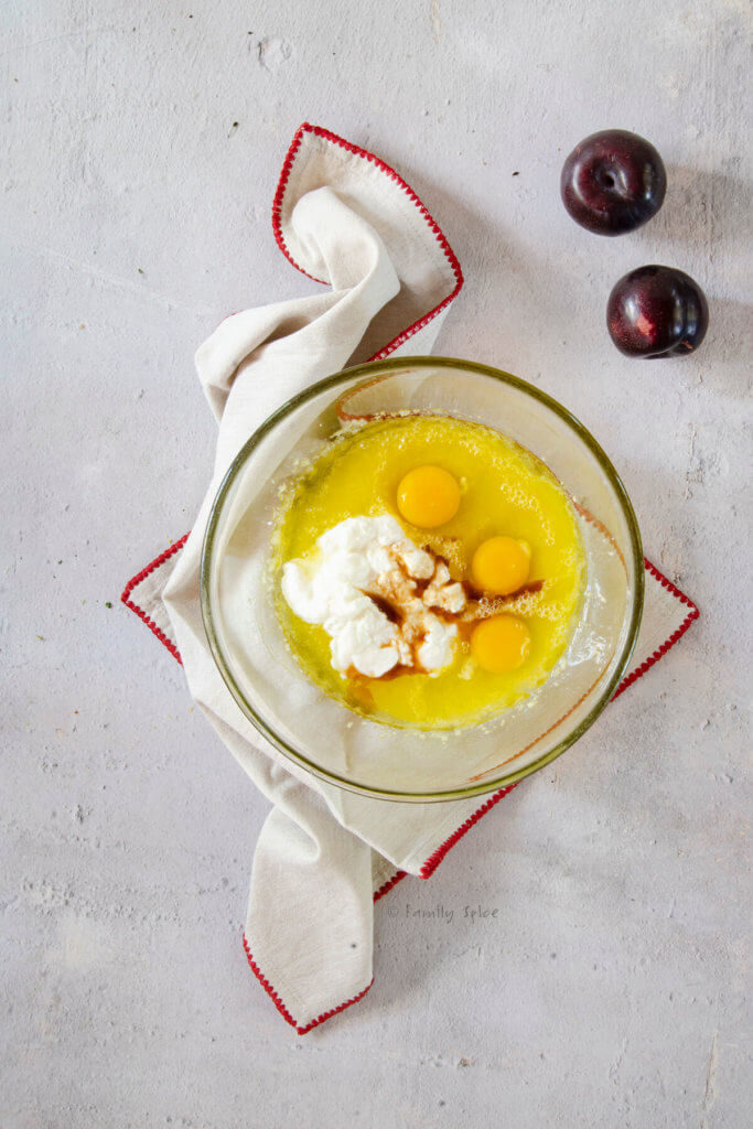 Adding yogurt, eggs and vanilla to olive oil-sugar mixture in a mixing bowl