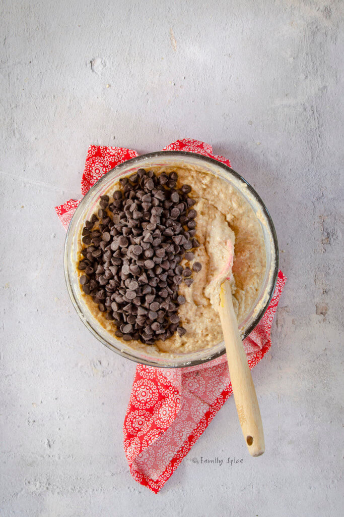 Adding chocolate chips to waffle batter in a glass mixing bowl