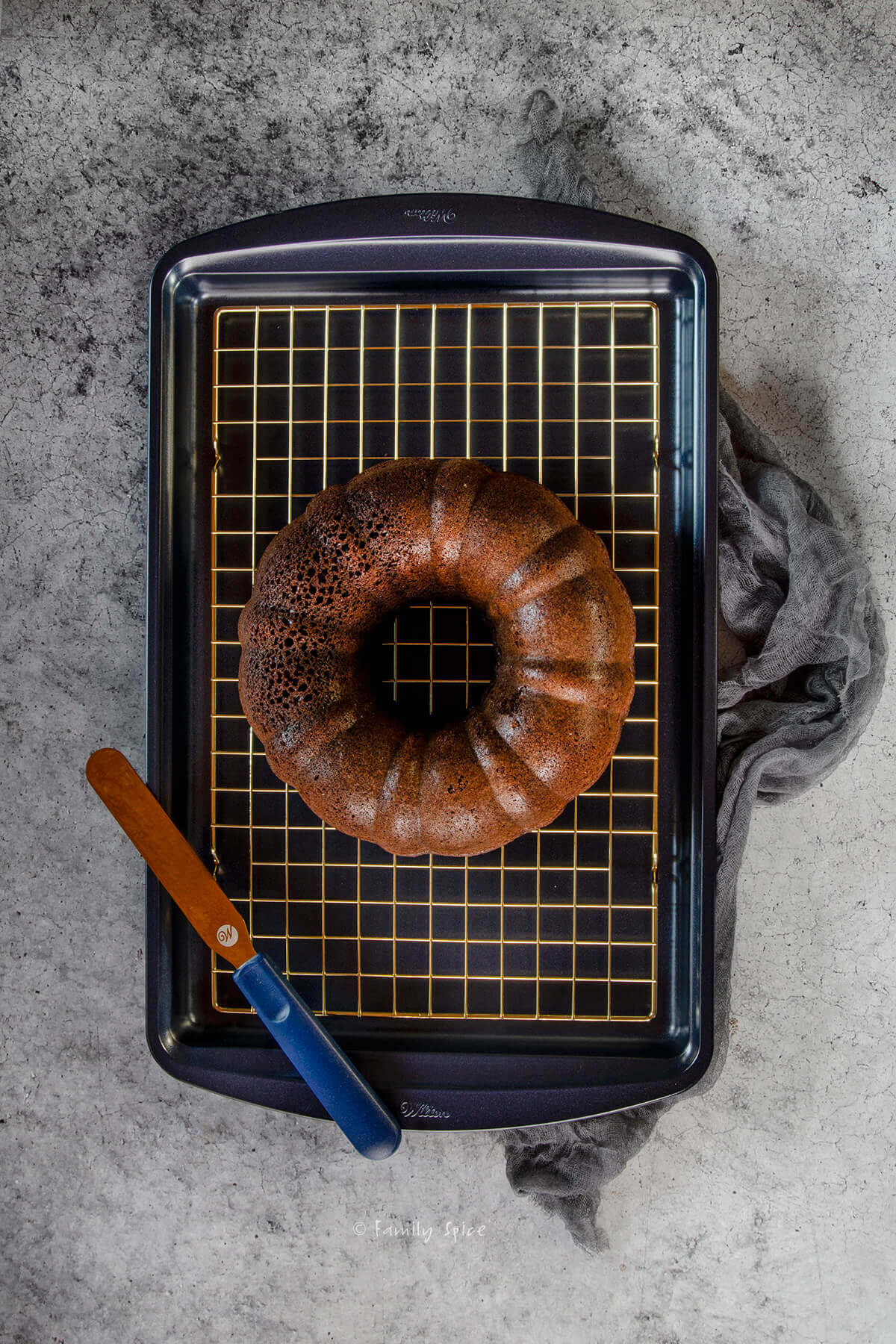 Chocolate guinness bundt cake cooling on a gold cooling rack over a navy blue baking sheet