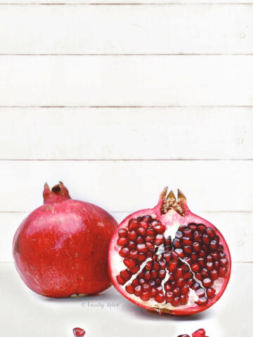 A whole pomegranate with a half pomegranate on a white background