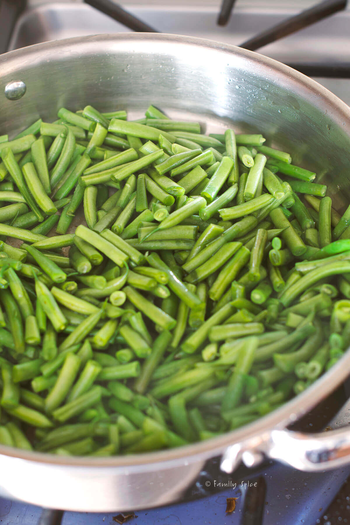 A stainless pan with sautéed green beans in it