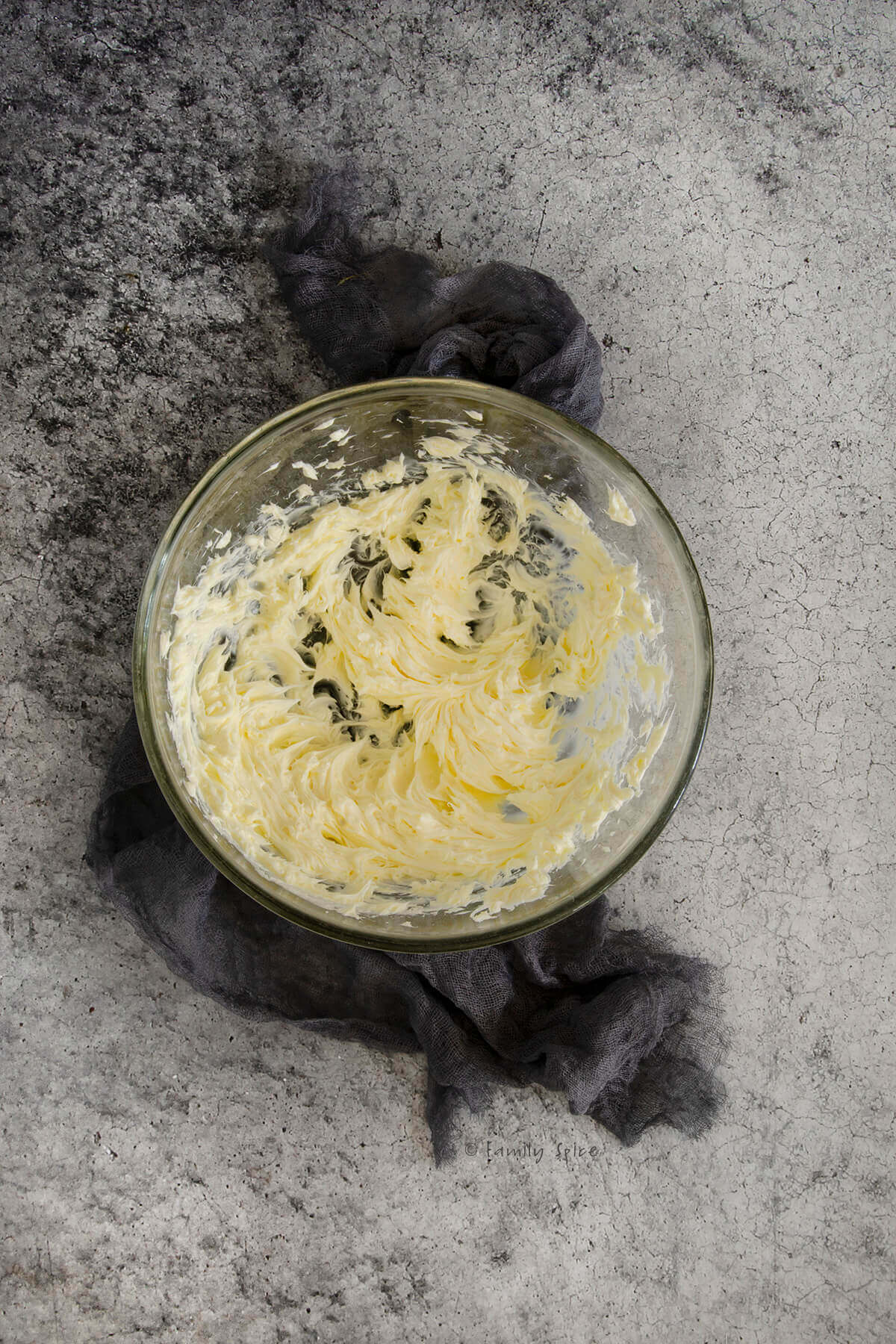 A glass mixing bowl with whipped butter in it.