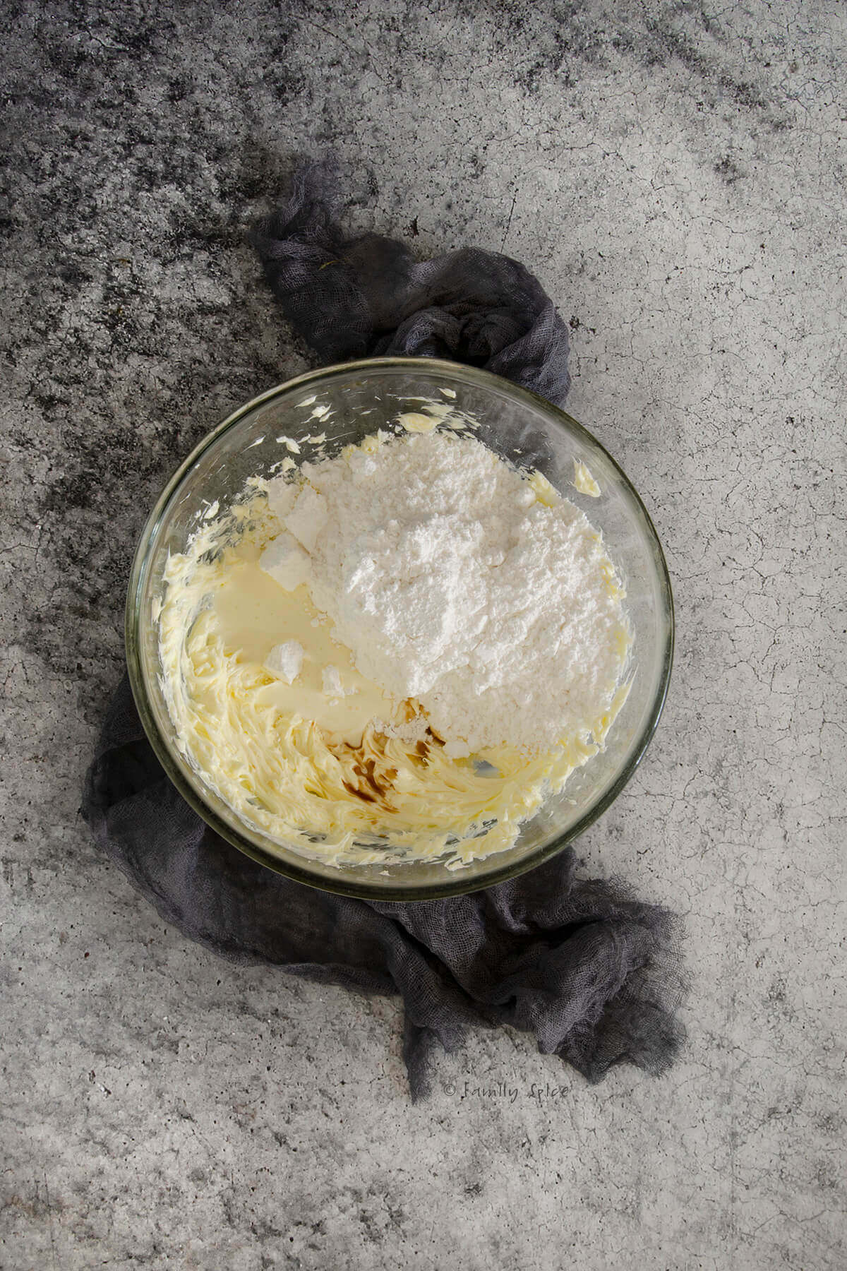 A mixing bowl with whipped butter, powdered sugar and vanilla in it