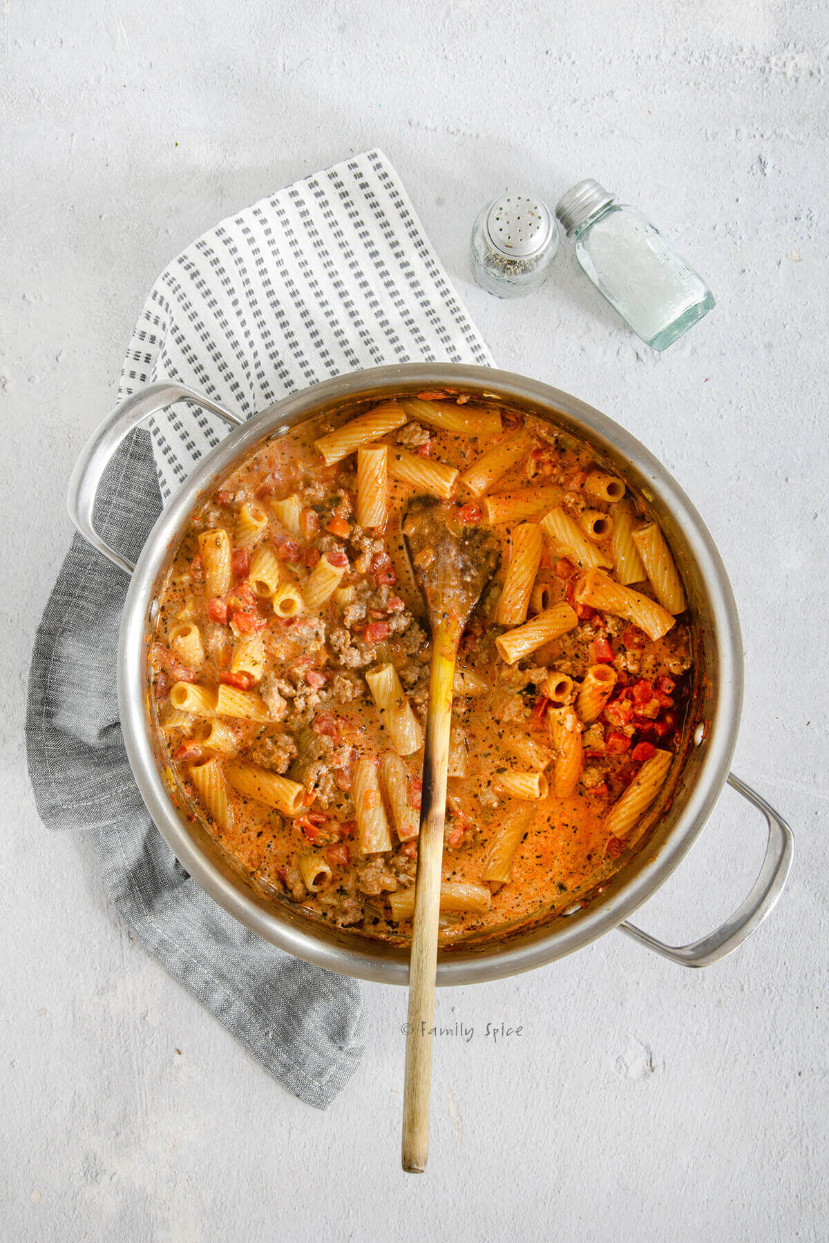 Bolognese sauce with partially cooked rigatoni in a stainless pot