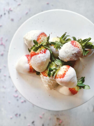 Closeup of a top view of white chocolate dipped strawberries on a white cake stand