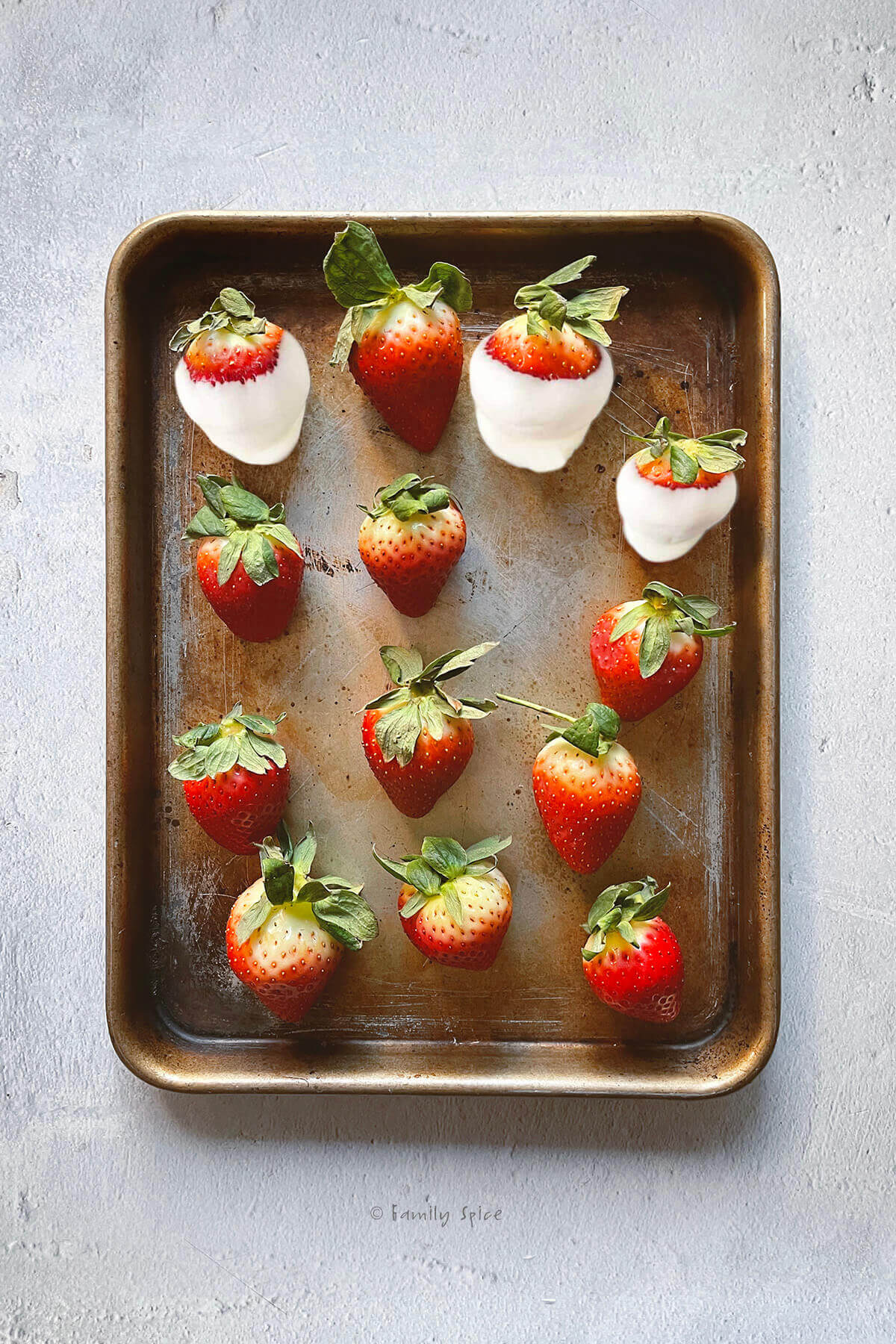 Large strawberries on small baking sheet with some of them dipped in white chocolate