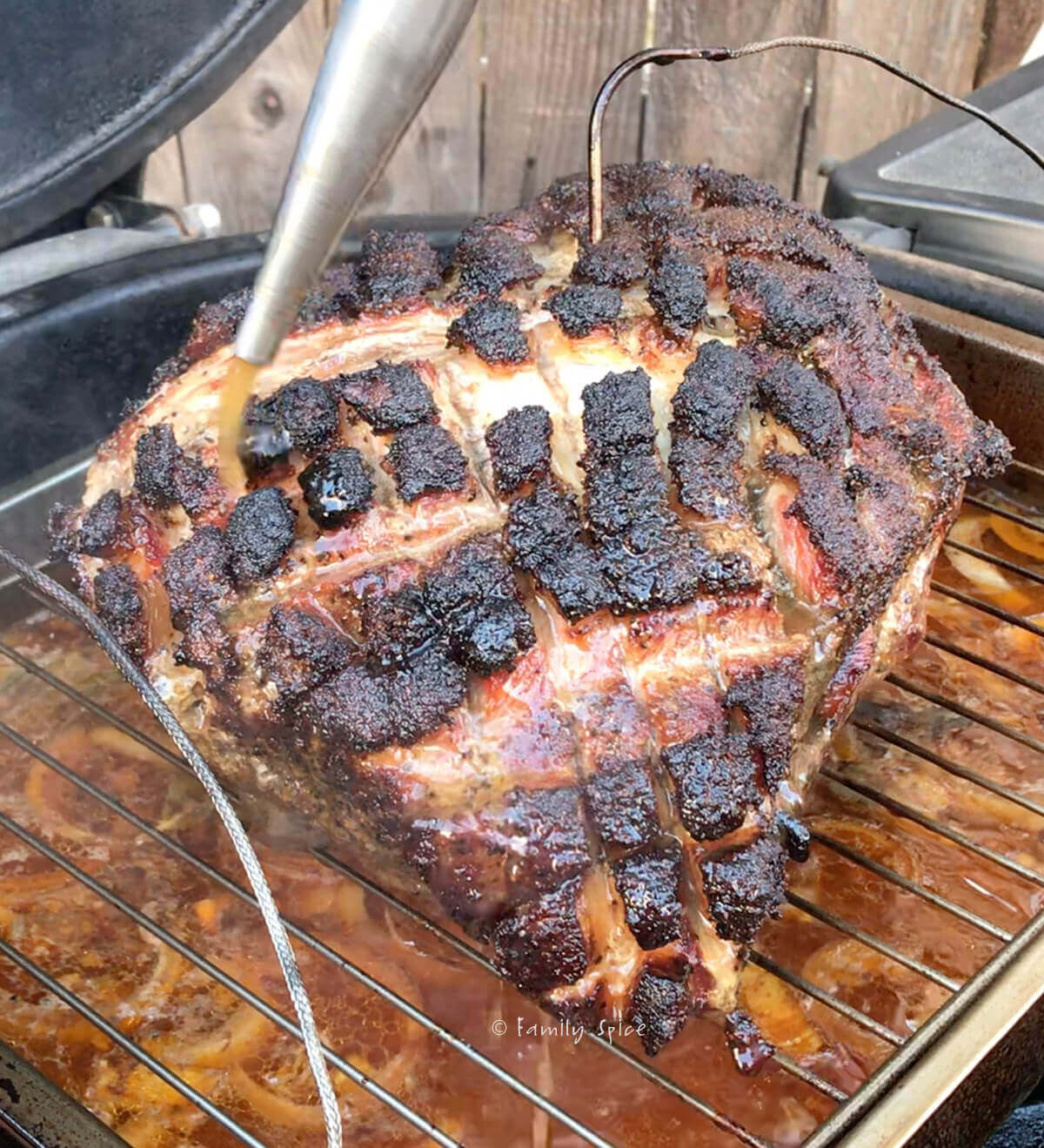 Basting a smoked pork butt in a kamado grill