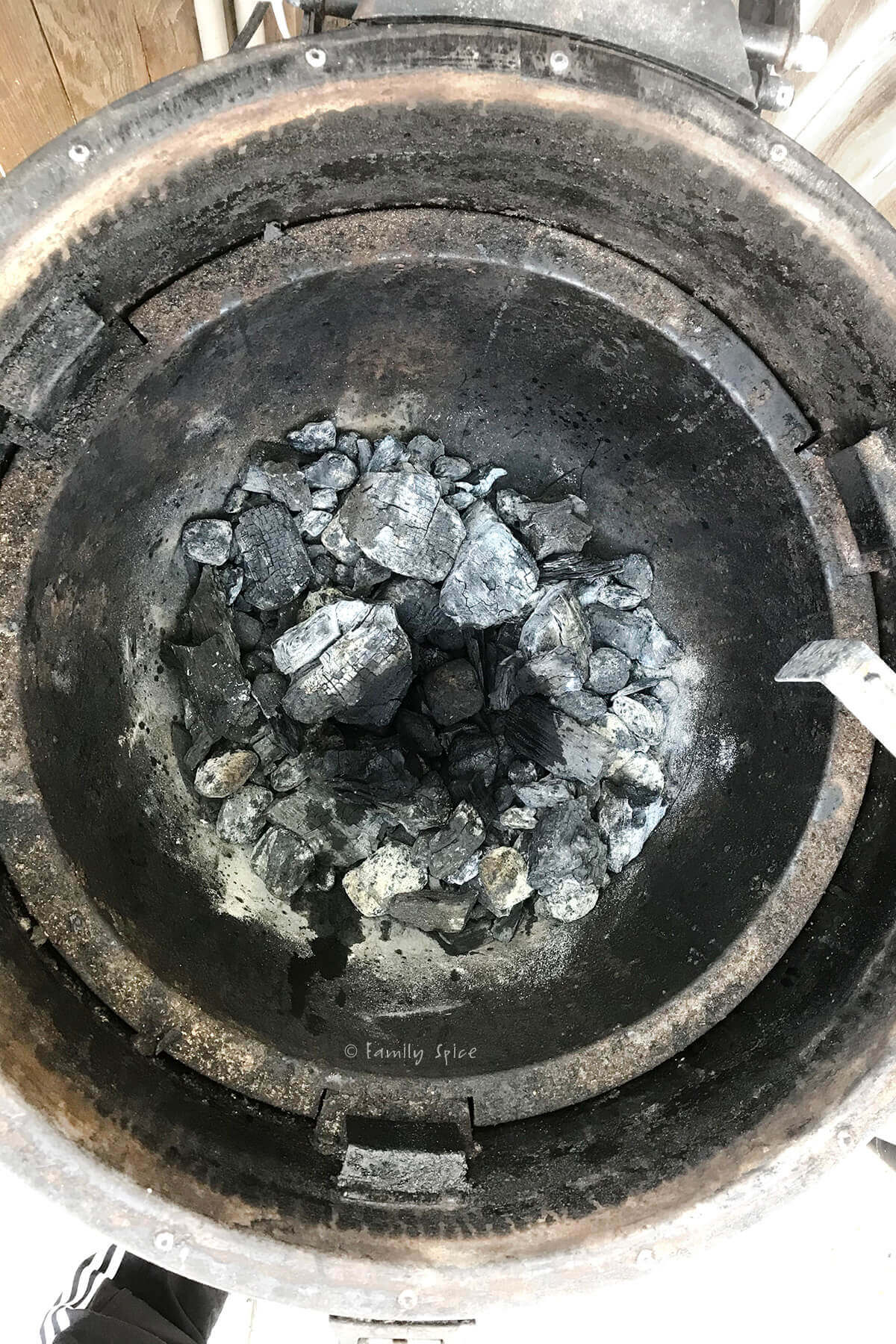 Looking inside of a round kamado grill with charred wood in it