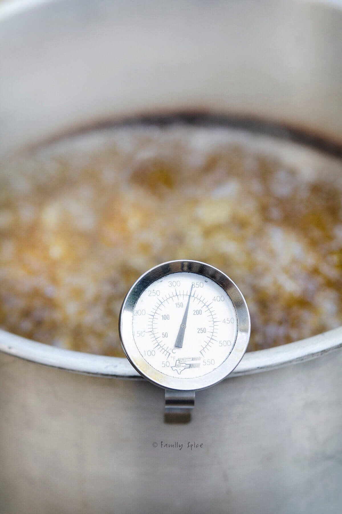 Closeup of a large pot with hot oil in it and thermometer attached