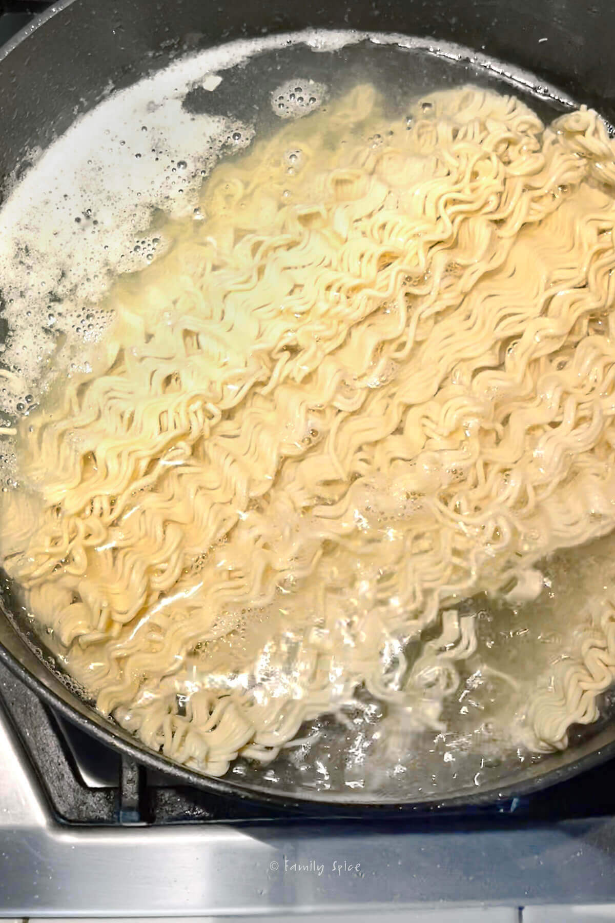 Ramen noodles added to boiling water in a large pot