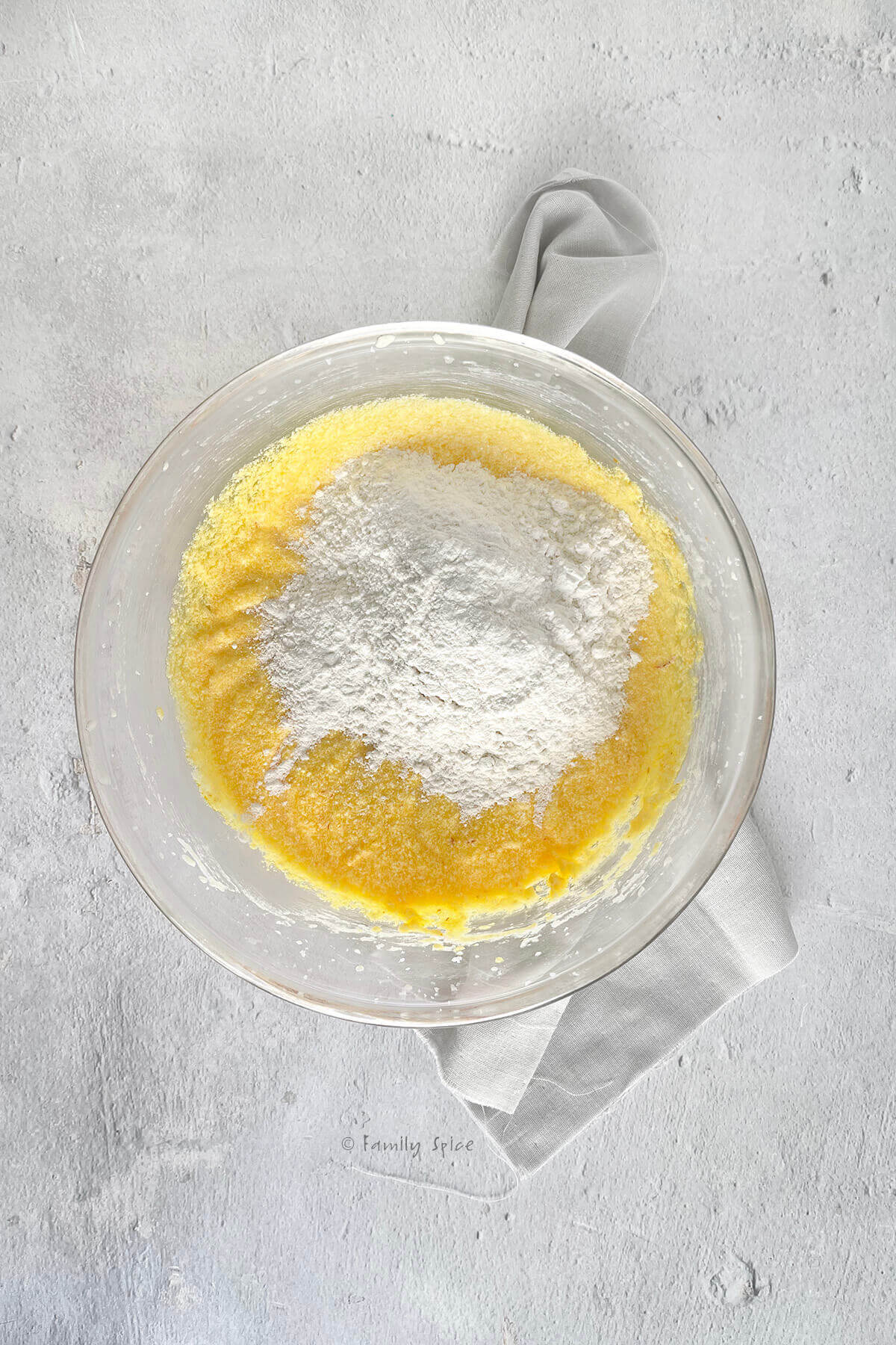 A mixing bowl with saffron batter in it and topped with flour mix