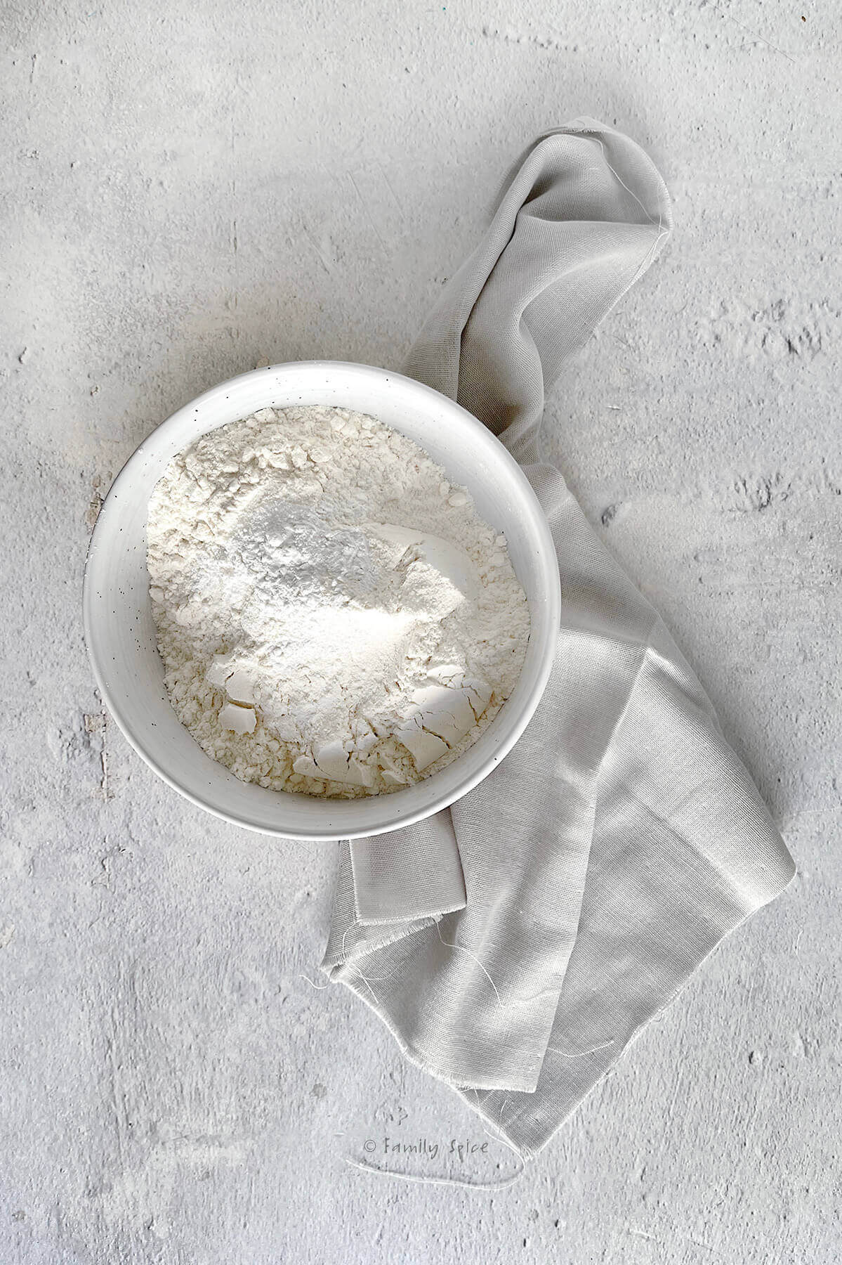 A white bowl with flour, baking powder and salt in it